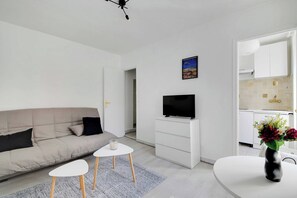 Ein modernes Wohnzimmer mit einer Couch, einem Flachbildfernseher, einem kleinen Couchtisch und einer dekorativen Vase.