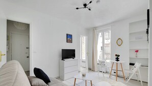 En moderne stue med sofa, fjernsyn, spisebord og udsigt ud