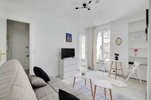 Ein modernes Wohnzimmer mit einer Couch, einem Fernseher, einem Esstisch und Blick ins Freie.