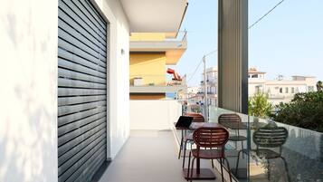 Un balcon avec une balustrade en verre, une table avec des chaises et un ordinateur portable.