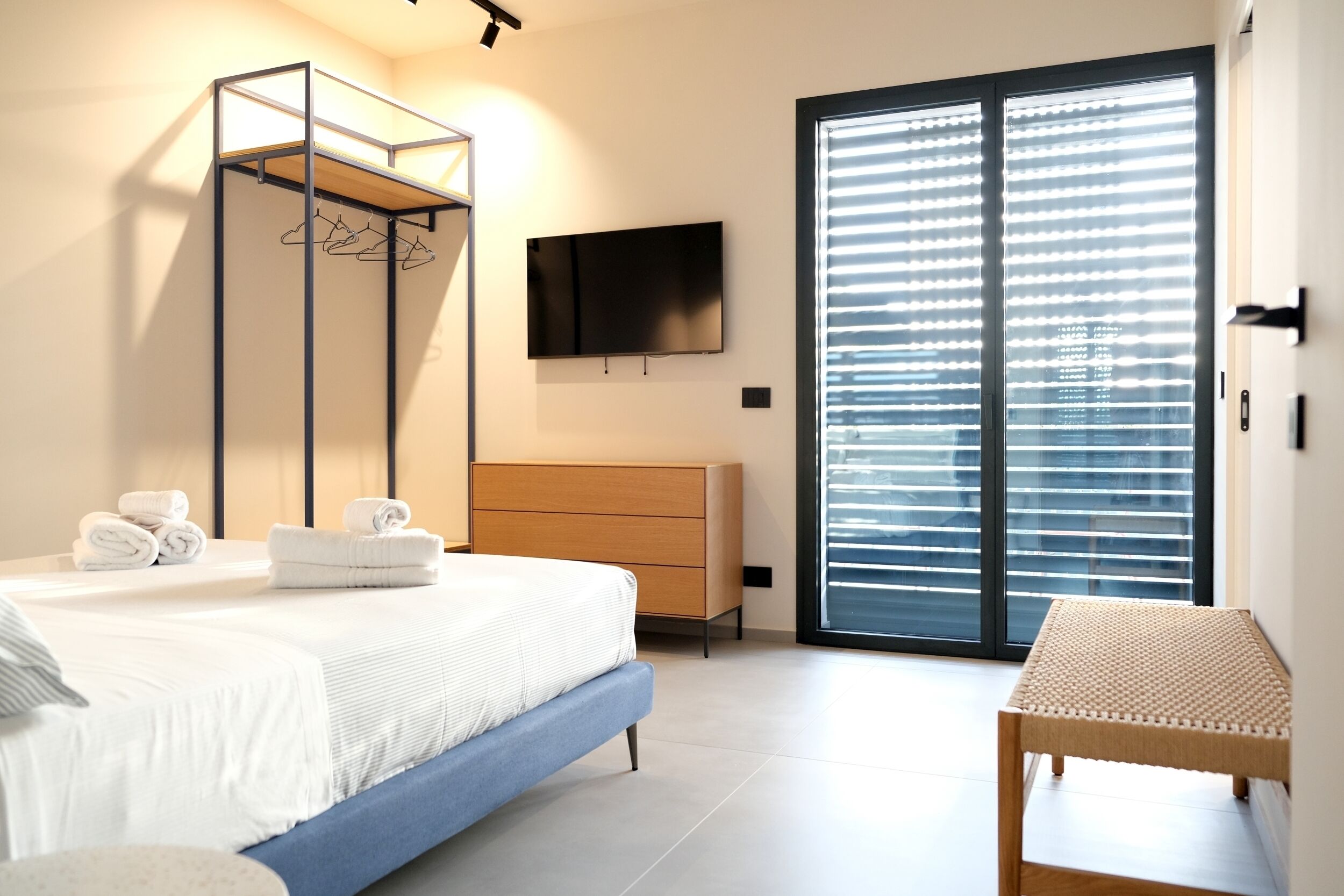 A bedroom with a bed, a dresser, a TV, and a sliding glass door.