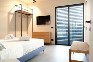 Quarto com uma cama, cômoda, televisão e porta de vidro deslizante.