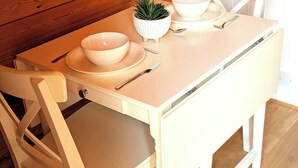 A white dining table with a bowl, a spoon, and a small plant.