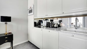 A modern kitchen with white cabinetry, a built-in oven, a coffee machine, and a sink with a faucet. - Charming studio 2P - Musée d'Orsay / Louvre (Paris)