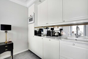 A modern kitchen with white cabinetry, a built-in oven, a coffee machine, and a sink with a faucet. - Charming studio 2P - Musée d'Orsay / Louvre (Paris)