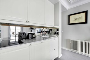 A modern kitchen with white cabinetry, a marble countertop, and a built-in sink. - Charming studio 2P - Musée d'Orsay / Louvre (Paris)