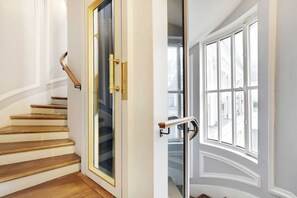 A staircase with a glass door and a window with a white frame. - Charming studio 2P - Musée d'Orsay / Louvre (Paris)