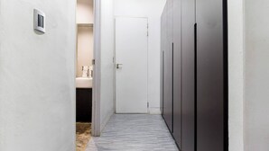 A narrow hallway with a door at the end, a small window, and a light switch on the wall.