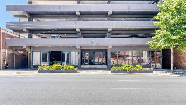 A modern building with a flat roof, a large entrance with glass doors, and a sign reading 'HALLMARK HOUSE'.