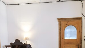 A room with a wooden desk, a chair, a lamp, and a wooden door.