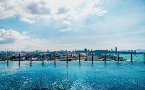 A cityscape with a clear blue sky and clouds, a large body of water, and several tall buildings in the background. - Sea View 2 Bed Room Best of Location (Pattaya)