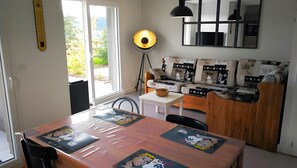 Una sala moderna con un sofá, una mesa de comedor con posavasos con motivos de dibujos animados, una lámpara de pie y un ventanal grande.