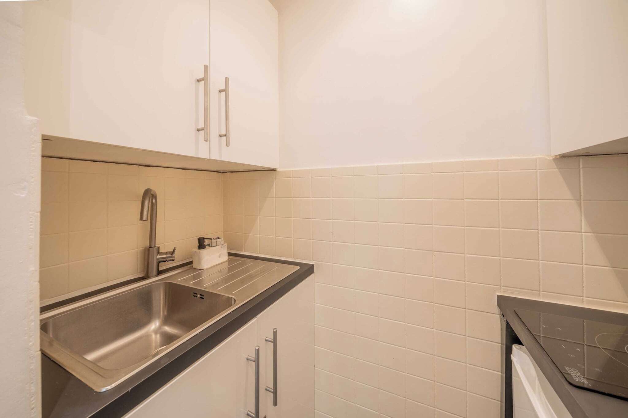 A small kitchen with a sink, cabinets, and a countertop.