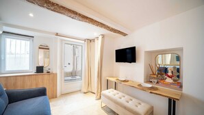 Quarto de hotel com uma janela grande, televisão de tela plana fixada na parede, um banco e uma pequena mesa com objetos decorativos.