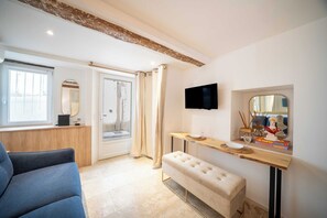 Ein Hotelzimmer mit großem Fenster, einem wandmontierten Flachbildfernseher, einer Bank und einem kleinen Tisch mit Dekoration.