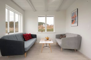 A modern living room with two sofas, a small table, and a window with a view of the outdoors. - New-build with sea views on Samsø (Samsø)