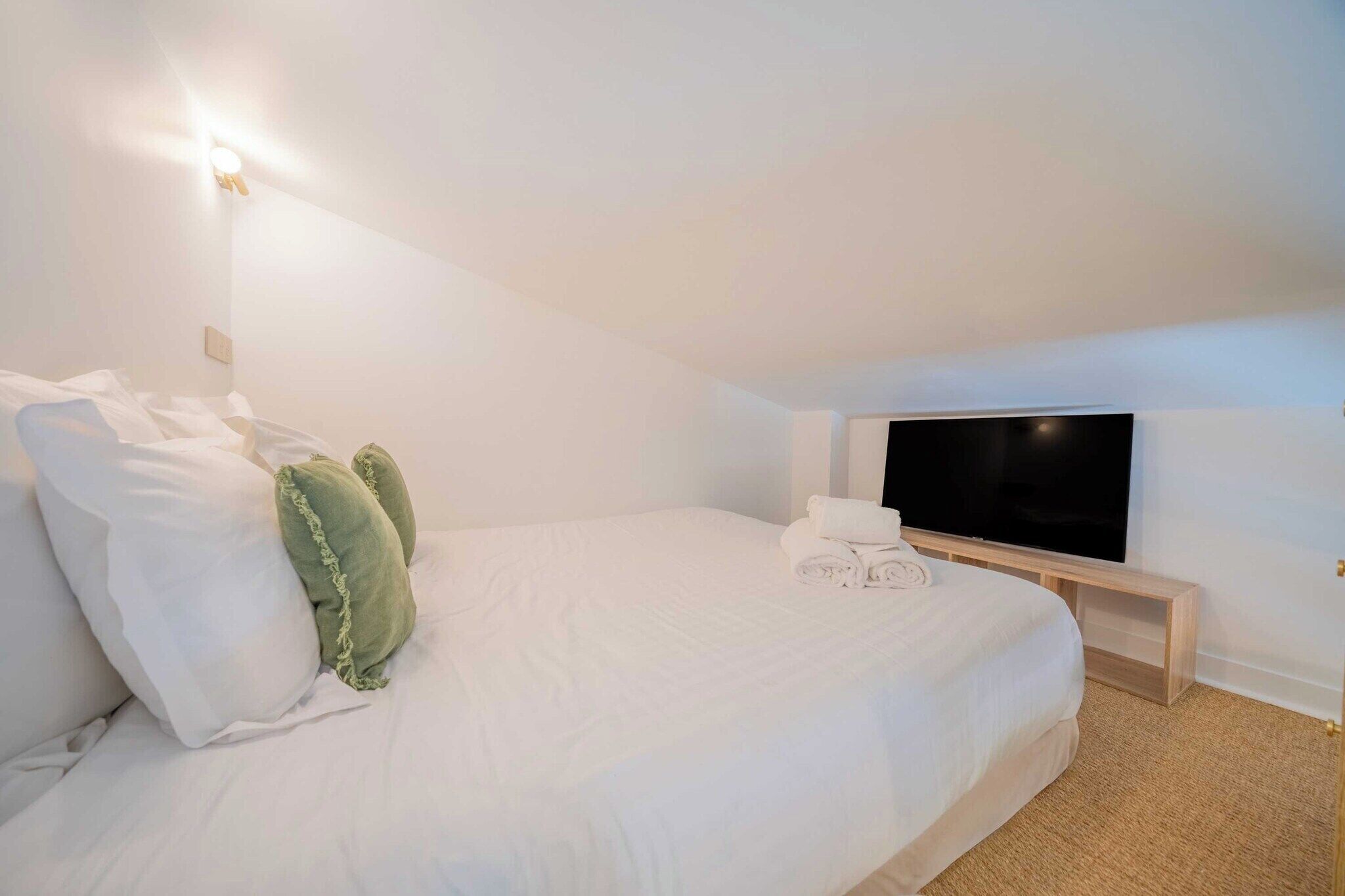 Une chambre d’hôtel équipée d’un lit, d’oreillers, d’un téléviseur à écran plat et d’une table de chevet.