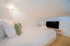 Une chambre d’hôtel équipée d’un lit, d’oreillers, d’un téléviseur à écran plat et d’une table de chevet.