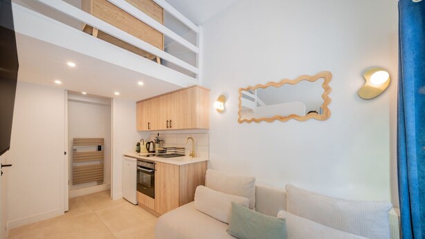 Un apartamento moderno con un entrepiso con dormitorio, una kitchenette y una sala de estar con sofá.