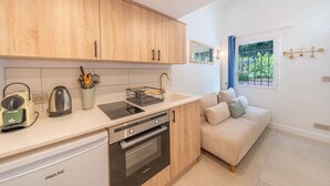 A compact kitchen with modern appliances, a built-in oven, and a dining area with a sofa. - Studio in a residence with pool - Saint-Tropez (Saint-Tropez)