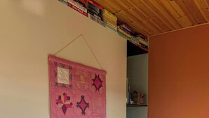 Et børneværelse med et pinkt quilt, træstole, en legestov og en reol fyldt med bøger.