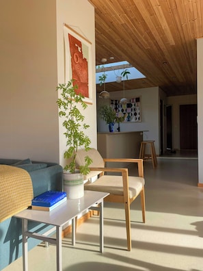A modern living room with a sofa, a table, a potted plant, and a bookshelf. - Retro 70s house with lake views in Jelling (Jelling)