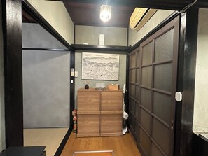 A traditional Japanese interior with a wooden cabinet, a painting, and a sliding door. - Rocket House, Traditional Japanese Home in Tokyo (Shinagawa City)