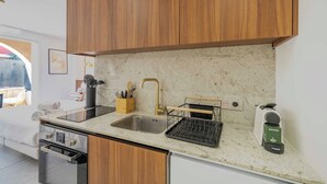 Une cuisine moderne avec des meubles en bois, un évier en acier inoxydable, une machine à café et un égouttoir à vaisselle.
