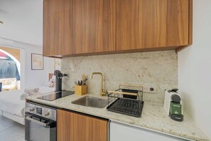 Una cuina moderna amb armaris de fusta, un rentatalls d'acer inoxidable, una màquina de cafè i un escorredor de plats.