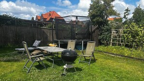 En trädgård med en grill, utomhusmöbler och ett trästaket.