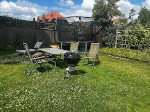 Ein Garten mit Grill, Gartenmöbeln und Holzzaun.