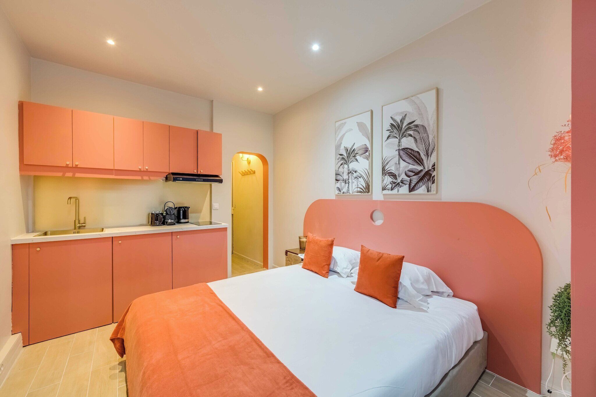 Ein Schlafzimmer mit einem Bett, einer Küchenzeile und zwei an der Wand befestigten Kunstwerken.