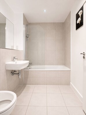 A modern bathroom with a sink, toilet, and bathtub. - Spacious 2BR Sleeps 7,  Long Stays (Greater London)