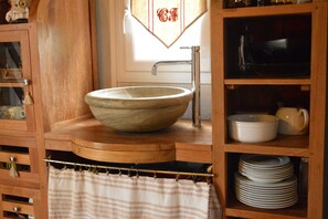 Eine Holz-Küche mit einer großen Schüsselspüle, einem Schrank mit Geschirr und einem Handtuchhalter.