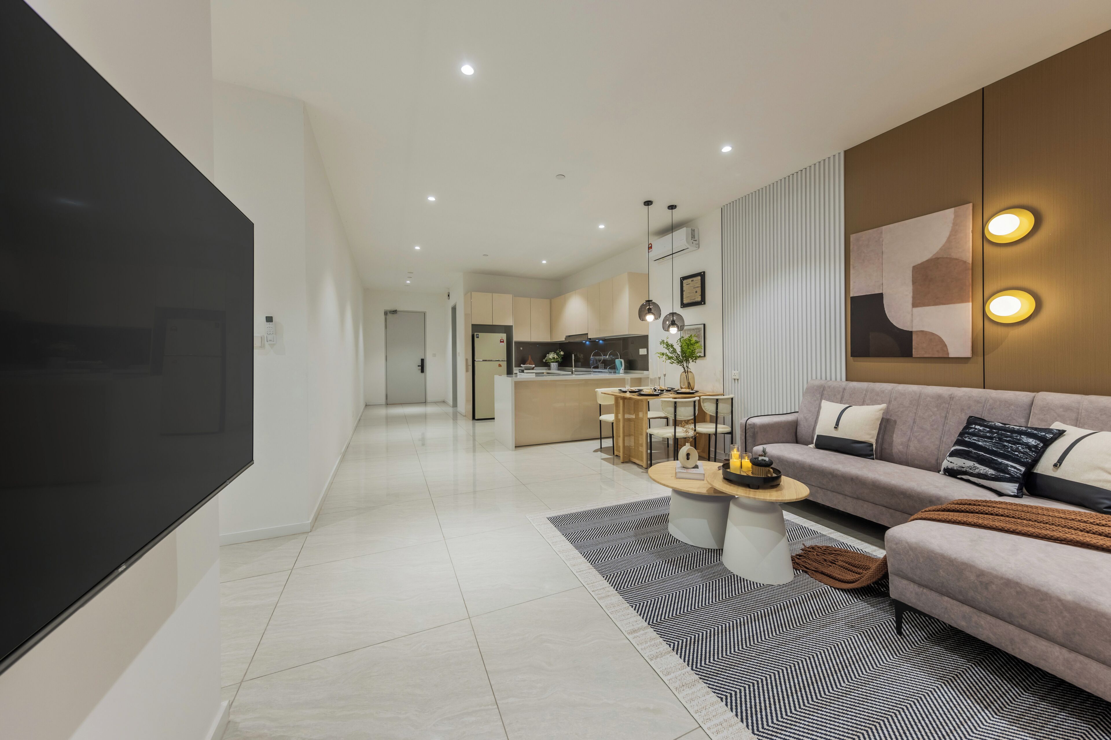 A modern living room with a sofa, coffee table, and a TV mounted on the wall.