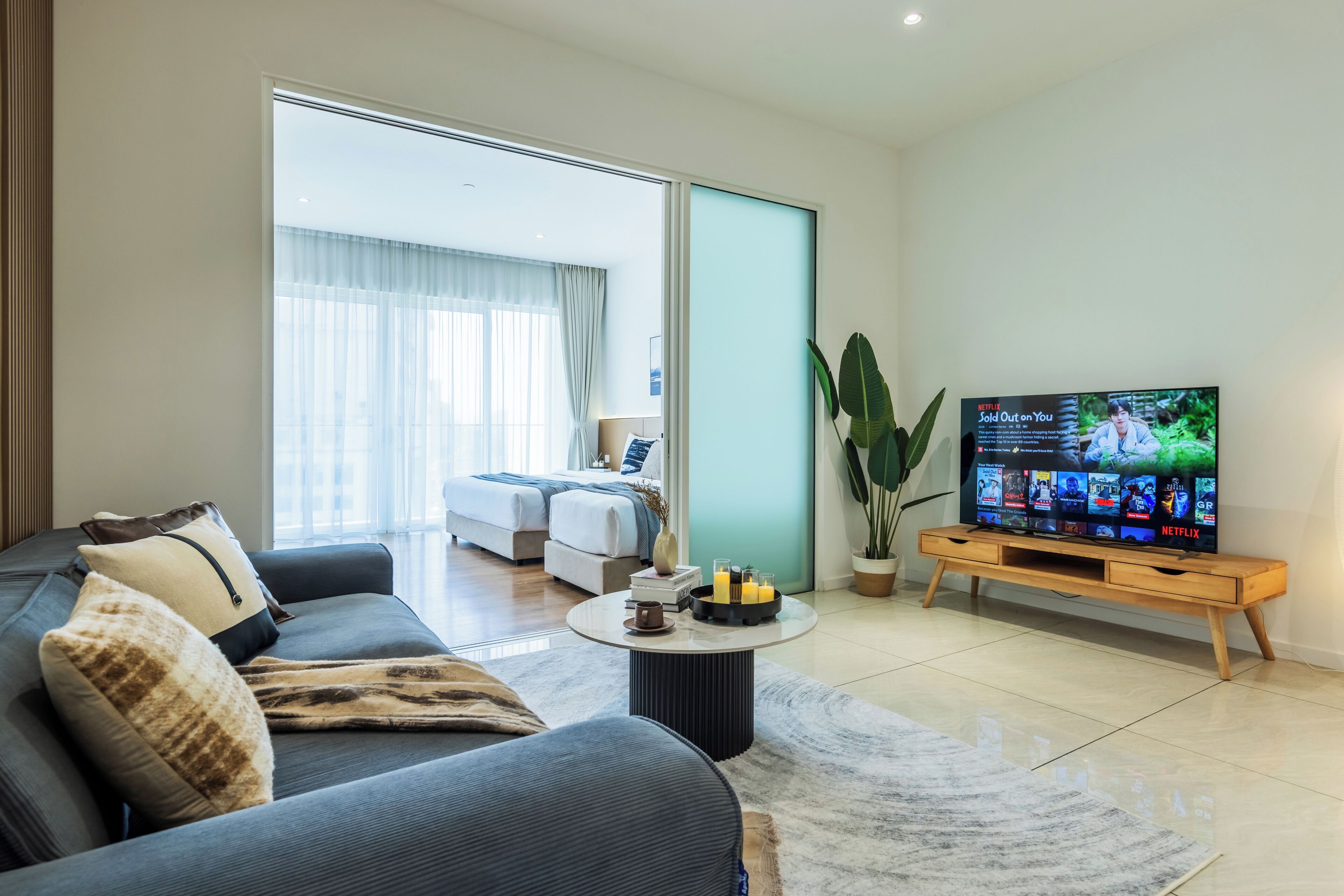 A modern living room with a sofa, coffee table, and a television displaying a show.