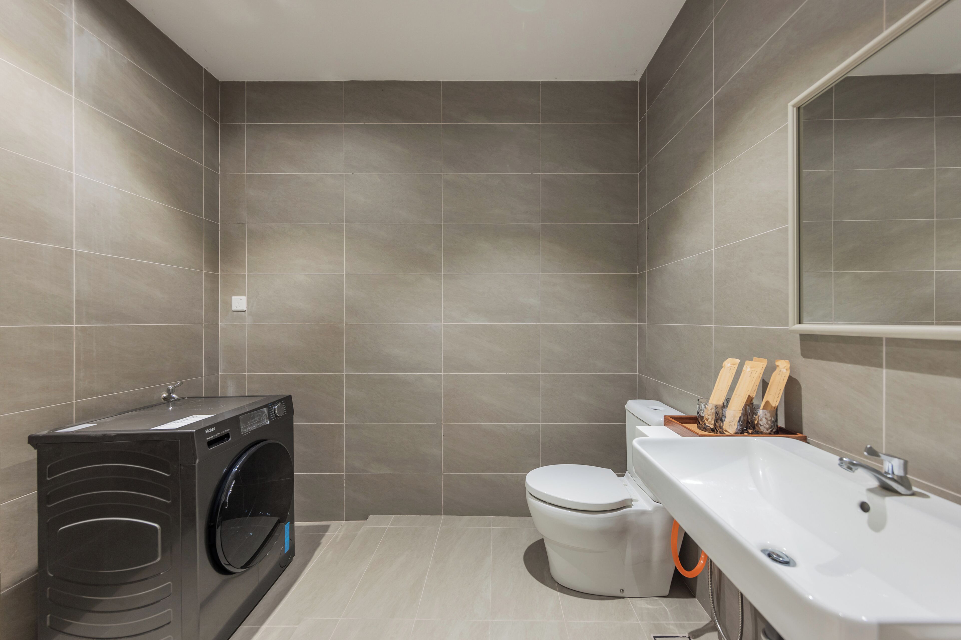A modern bathroom with a built-in washer, toilet, and sink.