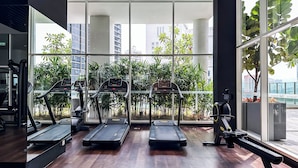 A gym with treadmills, exercise bikes, and weights, large windows with a view of buildings and greenery. - Veone Hotel  Kuala Lumpur (Kuala Lumpur)