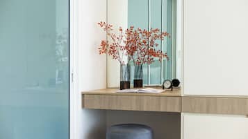A modern room with a wooden desk, a window, and a vase with red leaves.