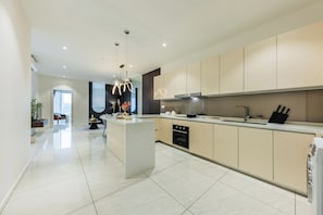 A modern kitchen with a central island, built-in oven, and stainless steel appliances.