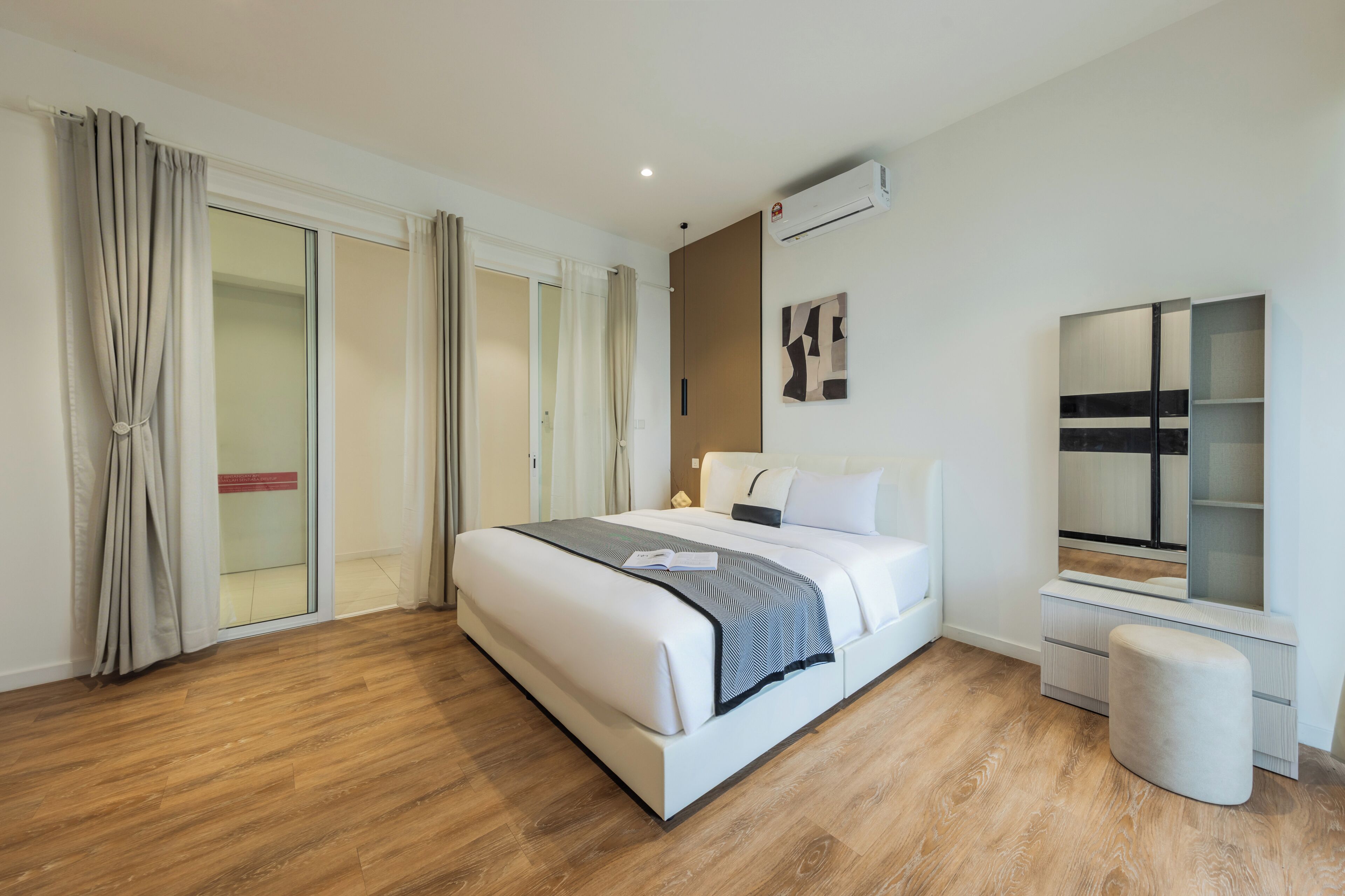 Ein modernes Hotelzimmer mit einem großen Bett, einem Nachttisch, einem Spiegel und einem Kleiderschrank.