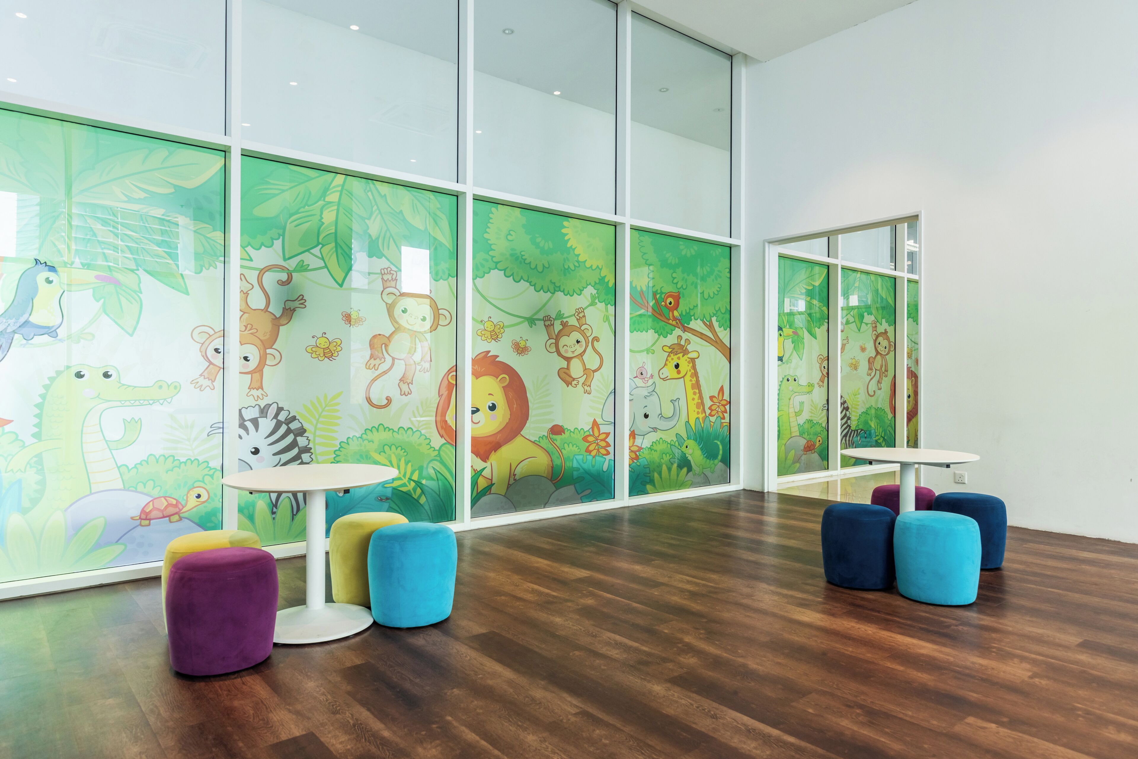 A children's play area with colorful furniture and jungle-themed wall decorations.