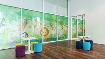 A children's play area with colorful furniture and jungle-themed wall decorations.