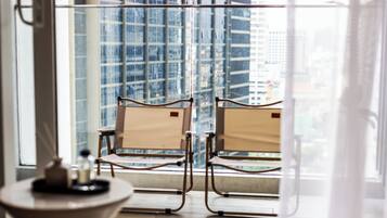 A room with two chairs facing a large window overlooking a cityscape.