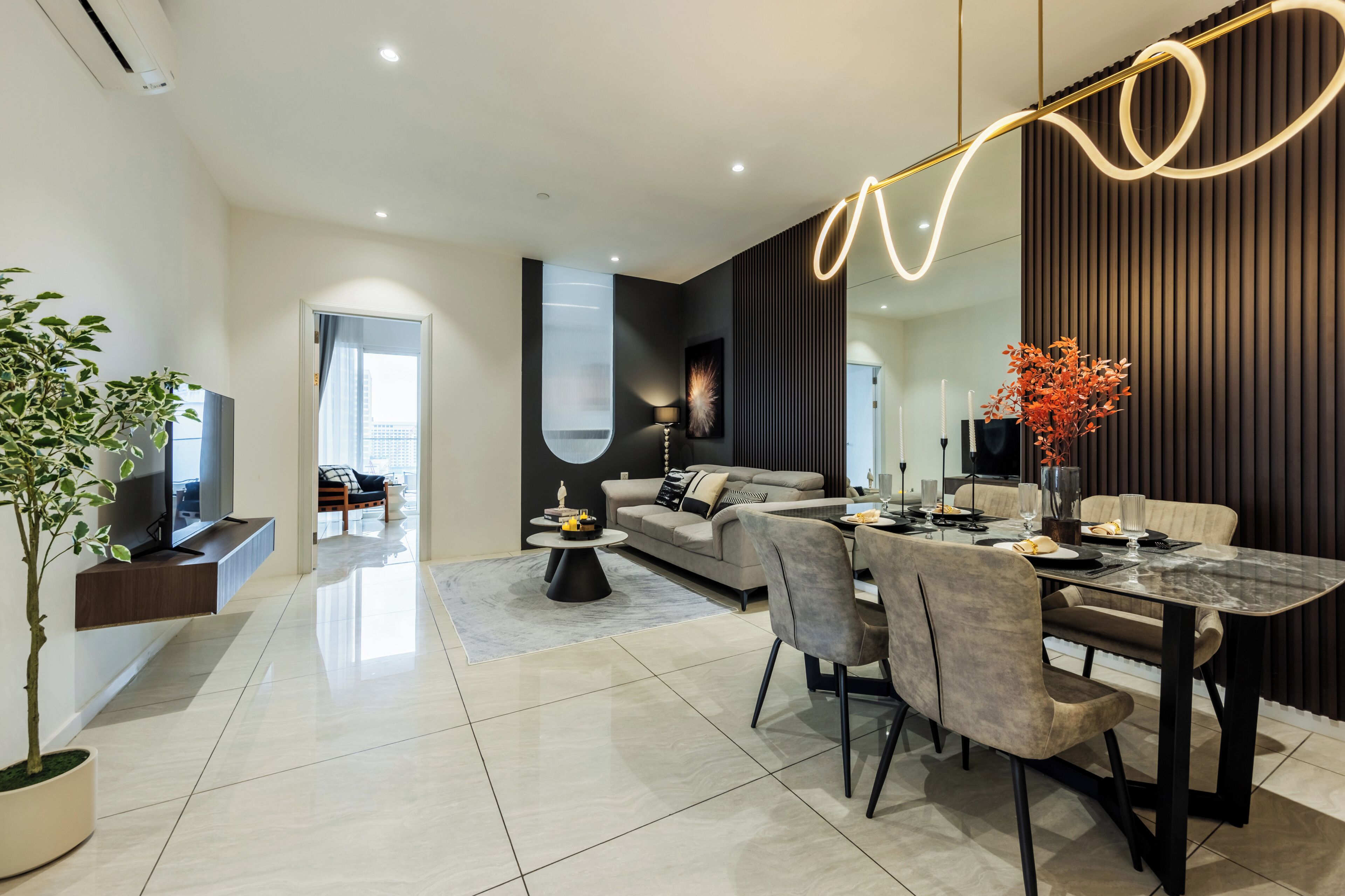 A modern living room with a dining area, a large window, and a flat-screen TV.