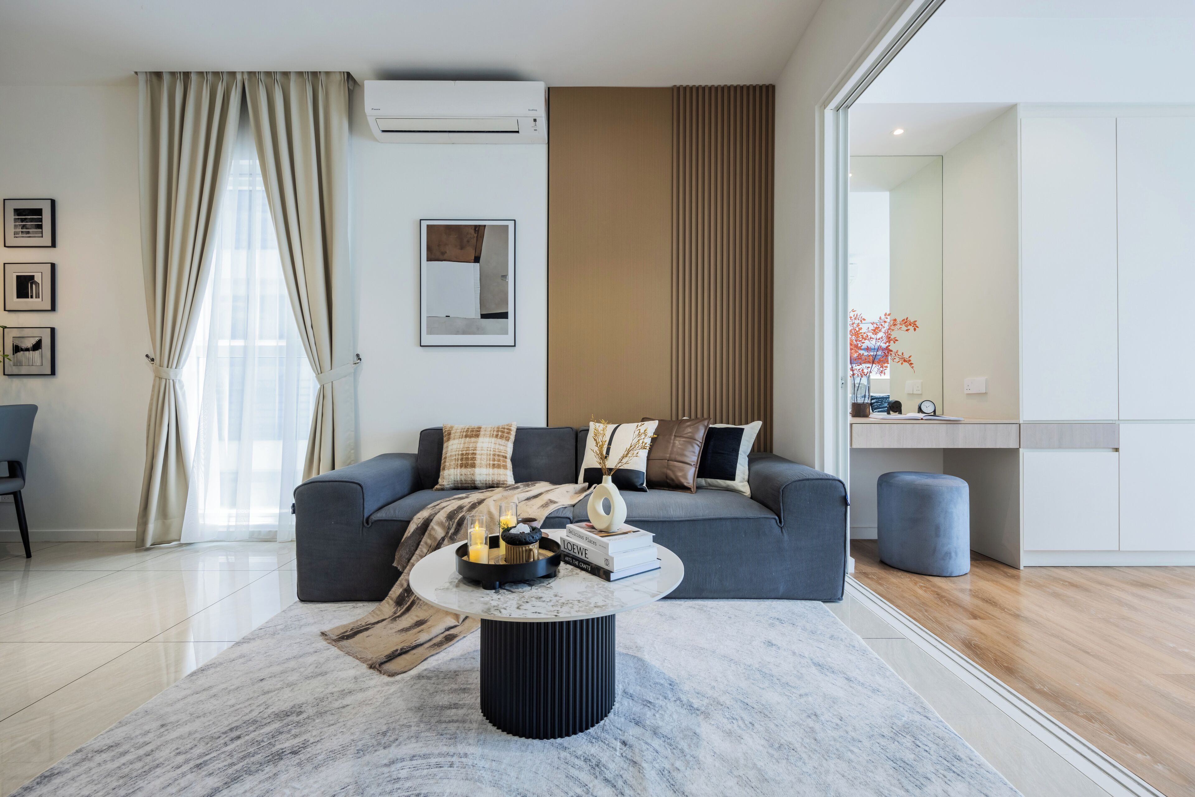 A modern living room with a sofa, a coffee table, and a large window with curtains.