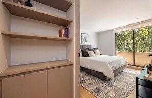 A bedroom with a bed, a window with a view, and built-in shelves. - Live in Provenza Modern 1 BR   security (Medellín)