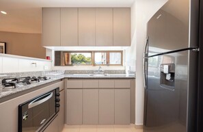 A modern kitchen with a built-in oven, a stainless steel refrigerator, and a window above the sink. - Live in Provenza Modern 1 BR   security (Medellín)