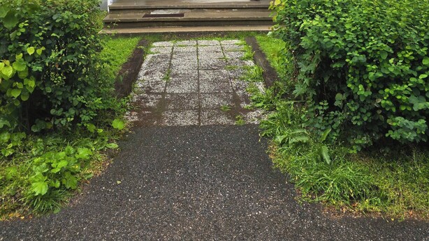 Ein gelbes Gebäude mit Hauseingang, einer kleinen Veranda und einem Weg zur Tür.