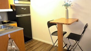 Une cuisine compacte équipée d’un four à micro-ondes, d’un four et d’un évier, une petite table à manger avec des chaises et une fenêtre donnant sur un paysage agréable.
